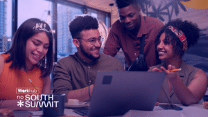 Equipe diversa reunida em ambiente colaborativo, analisando conteúdos no notebook durante o South Summit, representando troca de ideias, inovação e trabalho em equipe.