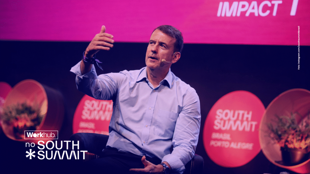 Palestrante no palco do South Summit Brasil falando sobre impacto e inovação, com identidade visual da Workhub aplicada.