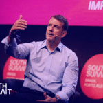 Palestrante no palco do South Summit Brasil falando sobre impacto e inova&ccedil;&atilde;o, com identidade visual da Workhub aplicada.