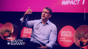 Palestrante no palco do South Summit Brasil falando sobre impacto e inovação, com identidade visual da Workhub aplicada.